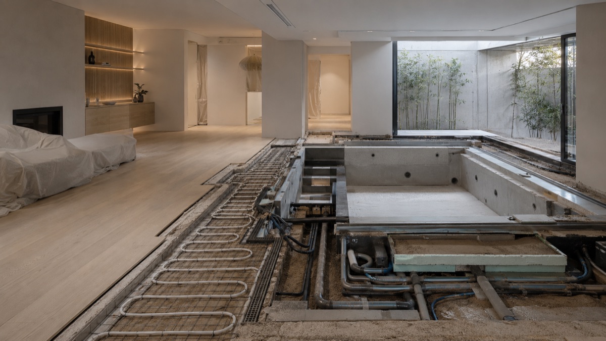 Salón de vivienda con el suelo radiante levantado y el vaso de una piscina interior en construcción